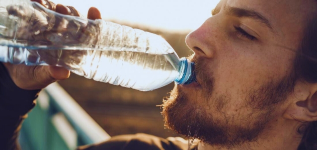 الشعور بالعطش المستمر؛ رجل ذو لحية شقراء يشرب الماء بعد عطش شديد.