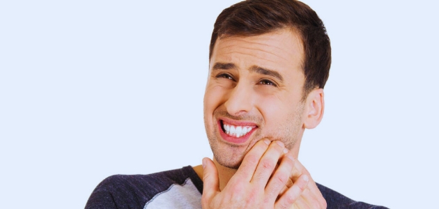 وجع الأسنان (Toothache)؛ رجل وسيم يضع يده على دقنه يشعر بألم في أسنانه.