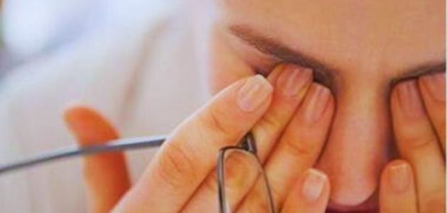 أعراض فقر الدم الشائعة؛ شخص يضع يديه على عينيه من أثر الإرهاق وبين أصابعه نظارة.