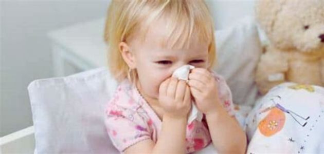 علاج احتقان الحلق والبلغم؛ طفلة شقراء تضع منديلًا على أنفها وفمها.